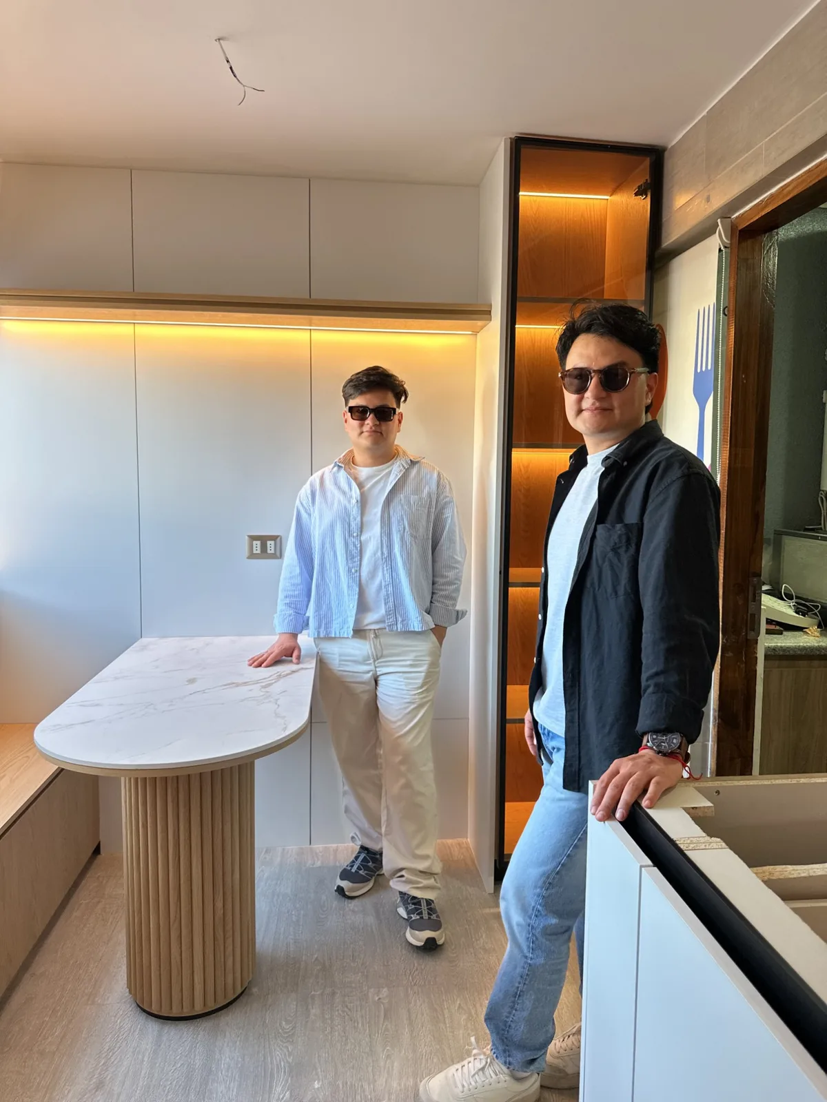Yanfer y Genderson García junto a la mesa de cubierta de mármol y base acanalada de roble, en una cocina de Arquimueble recién instalada